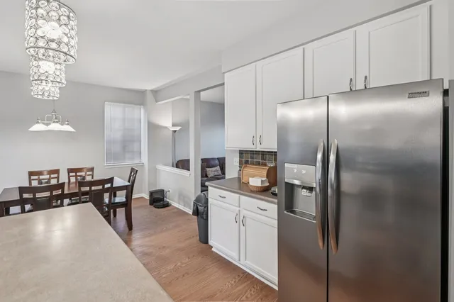 a kitchen with stainless steel appliances a refrigerator a stove a dining table and chairs with wooden floor