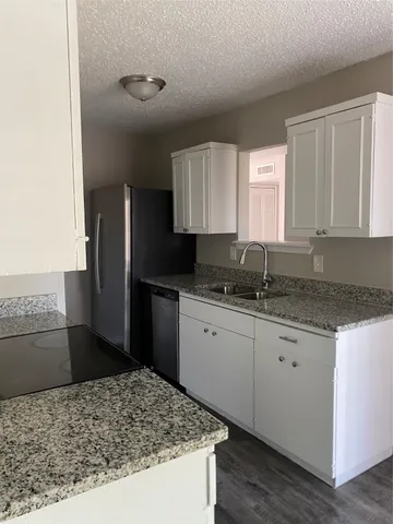 a kitchen with granite countertop a sink and a refrigerator