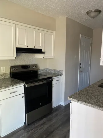 a kitchen with granite countertop white cabinets and black appliances