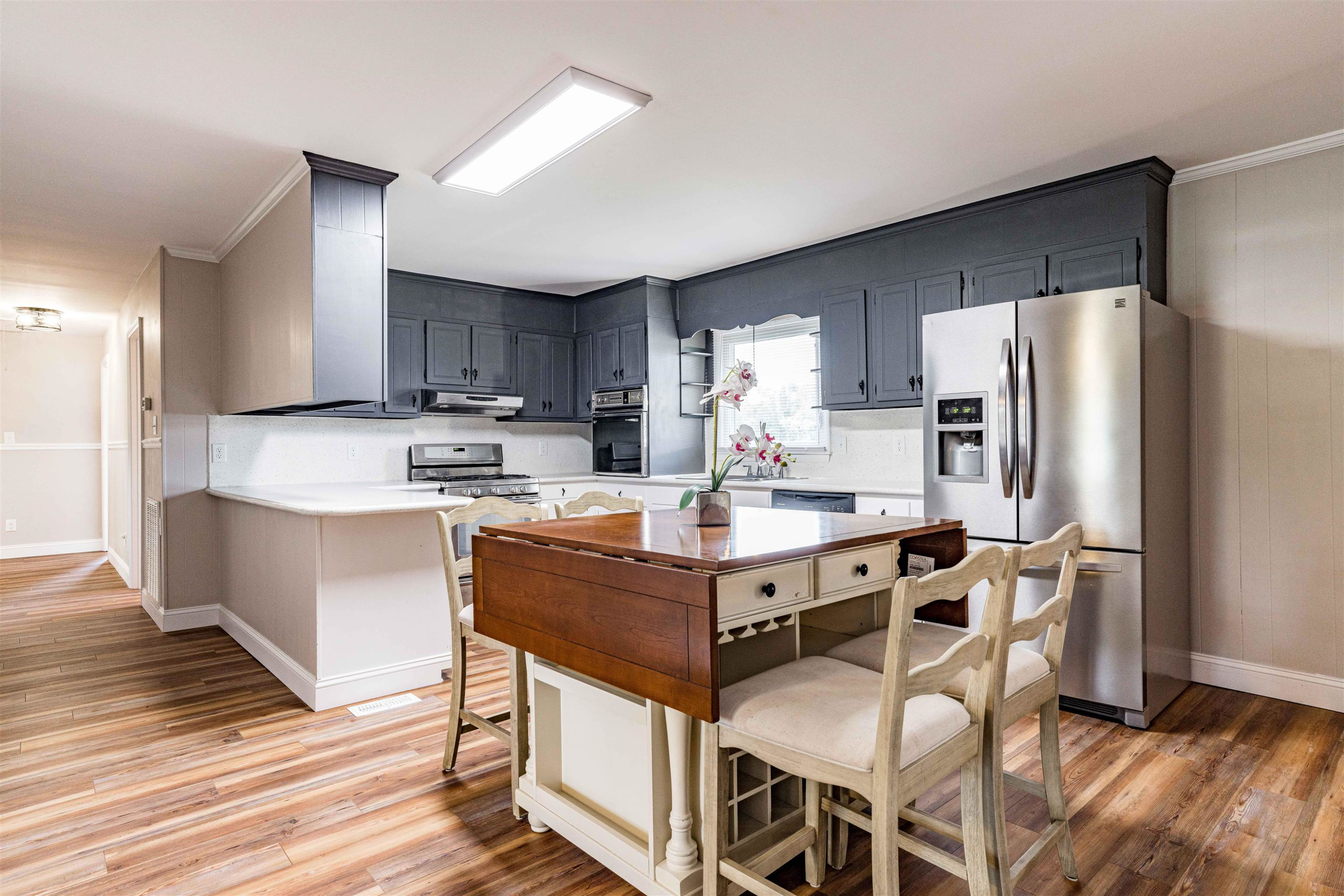 420 Faith Church Road Four Oaks, NC 27524 - Photo 17 of 36 a kitchen with stainless steel appliances granite countertop a stove a refrigerator a sink a dining table and chairs with wooden floor