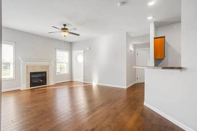 an empty room with wooden floor fireplace and windows