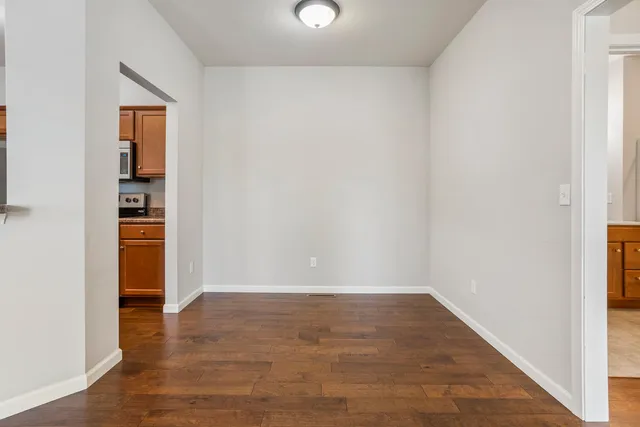 an empty room with wooden floor closet and windows