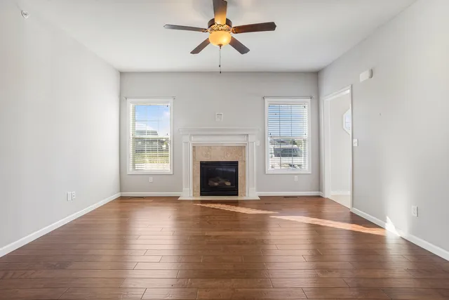 a view of an empty room with window and wooden floor