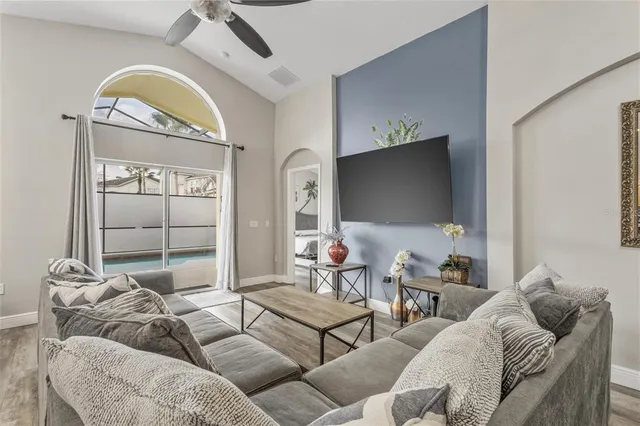 a living room with furniture a flat screen tv and a floor to ceiling window