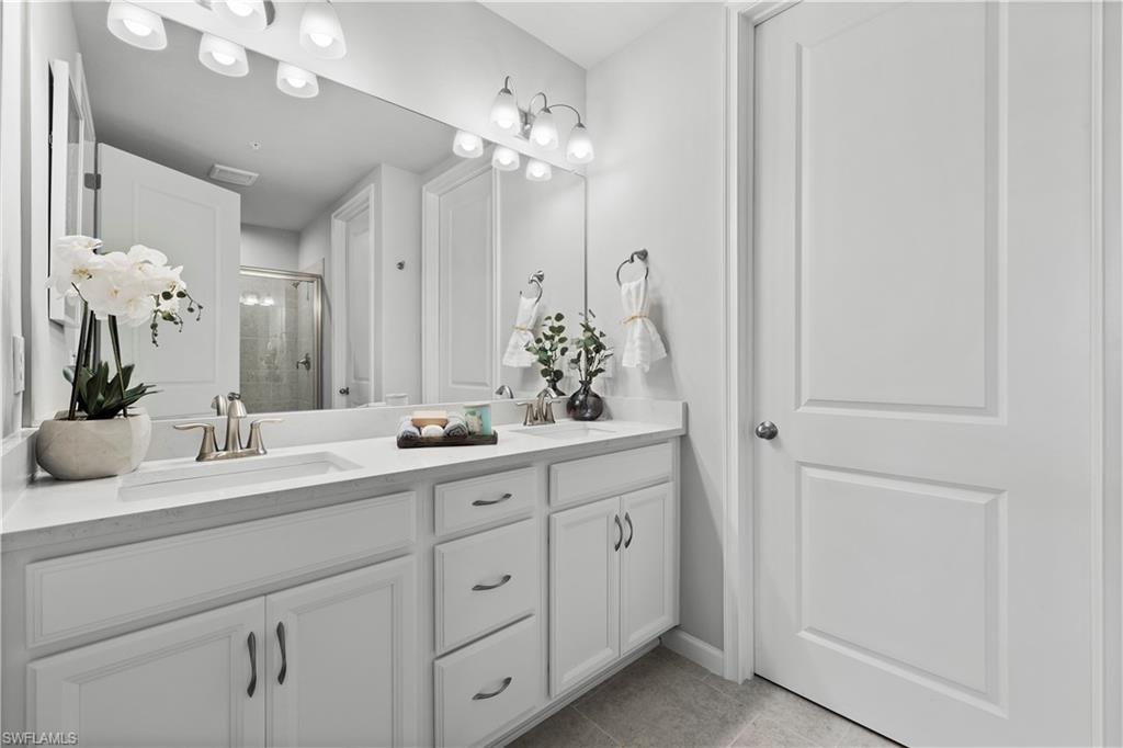 4676 Arboretum Circle, Unit 102 Naples, FL 34112 - Photo 28 of 35 a bathroom with a double vanity sink and a mirror