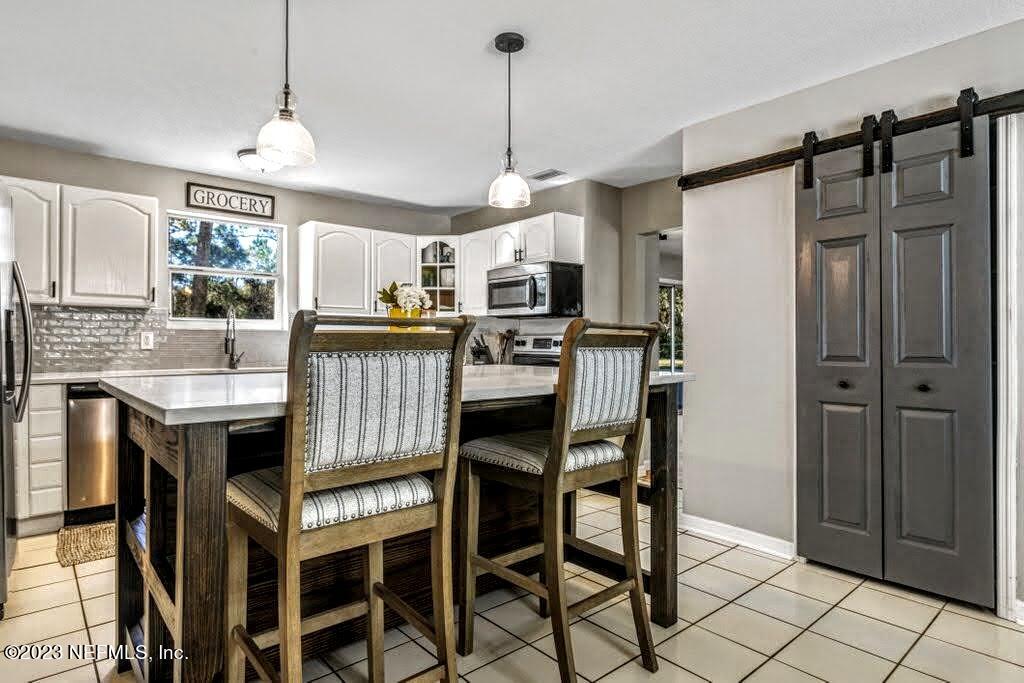 4233 Oak Lane St. Augustine, FL 32086 - Photo 14 of 40 a kitchen with granite countertop a table chairs microwave and refrigerator