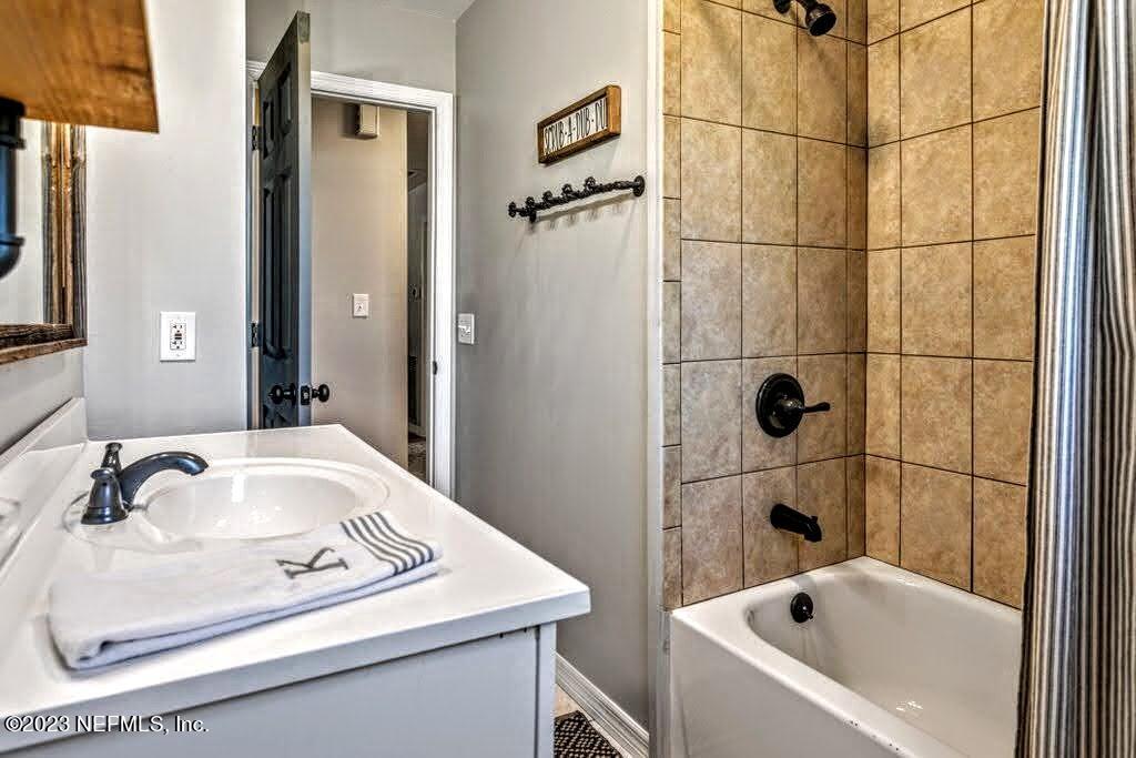 4233 Oak Lane St. Augustine, FL 32086 - Photo 27 of 40 a bathroom with a sink and mirror with bathtub