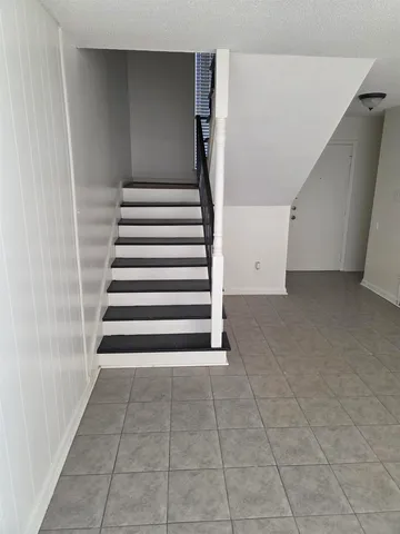 a view of an empty room with stairs and a ceiling fan