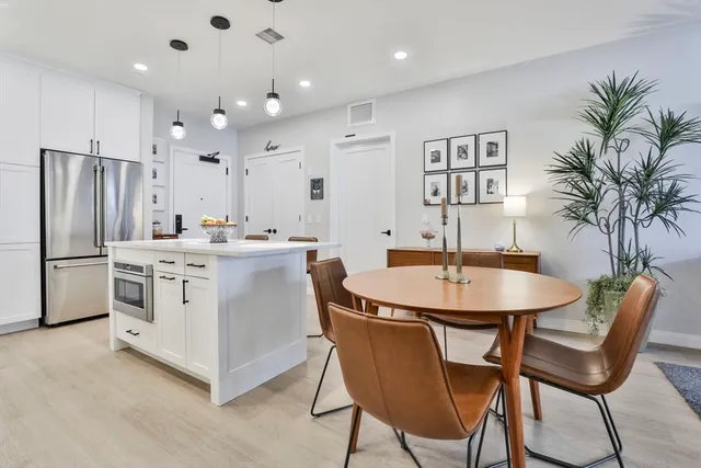 a kitchen with stainless steel appliances a white table chairs and a refrigerator