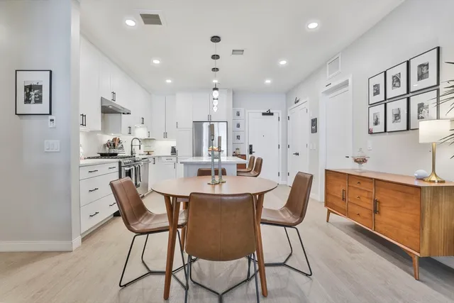 a dining room with stainless steel appliances kitchen island granite countertop a kitchen island and chairs in it