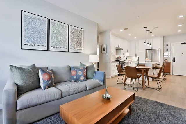 a living room with furniture a rug and kitchen view