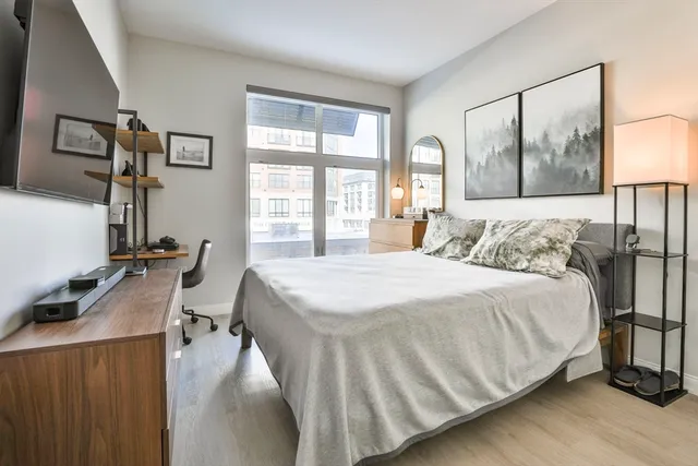 a bedroom with a bed a mirror and a large window