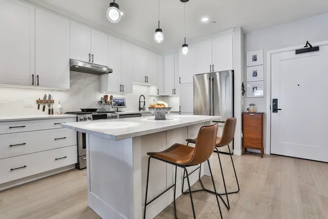 a kitchen with stainless steel appliances kitchen island granite countertop a table chairs refrigerator and sink