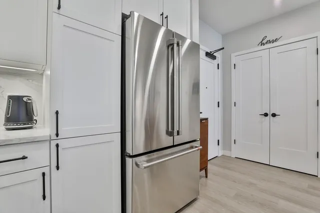 a view of a refrigerator in kitchen and white cabinets