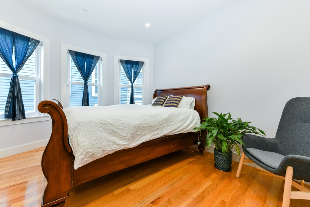 66 Wyman Street, Unit 1 Boston, MA 02130 - Photo 25 of 34 a bedroom with a bed chair and wooden floor