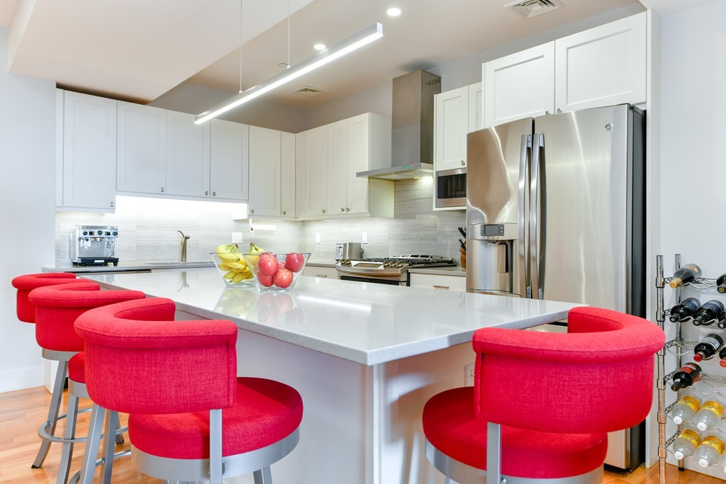66 Wyman Street, Unit 1 Boston, MA 02130 - Photo 5 of 34 a kitchen with stainless steel appliances kitchen island granite countertop a refrigerator and a sink
