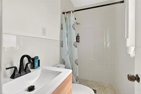 a bathroom with a sink a toilet a shower and mirror