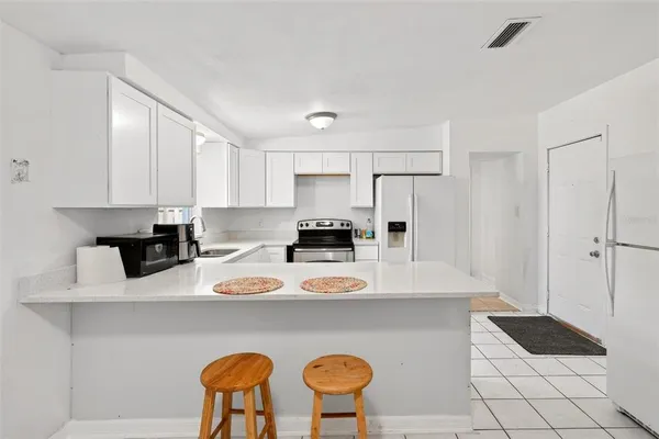 a kitchen with stainless steel appliances granite countertop a sink a stove a refrigerator a white table and chairs