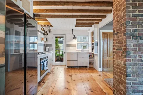 a room with stainless steel appliances kitchen island granite countertop a refrigerator and a wooden floor