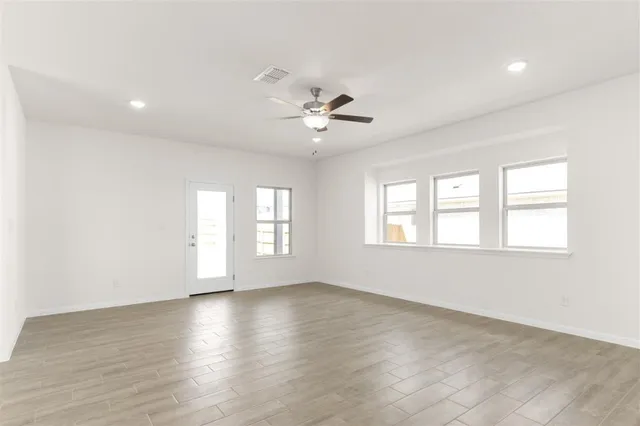 a view of an empty room with a window and wooden floor