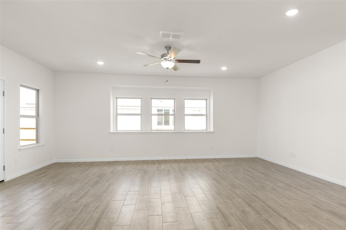 709 Paddock Lane Georgetown, TX 78626 - Photo 14 of 35 an empty room with wooden floor ceiling fan and windows