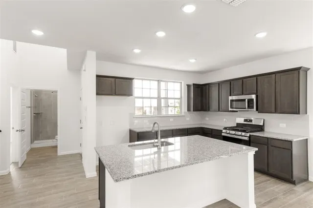 a kitchen with kitchen island granite countertop a sink wooden cabinets and stainless steel appliances