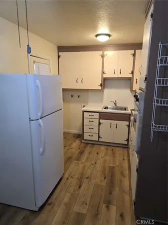 a kitchen with granite countertop a refrigerator a sink and white cabinets