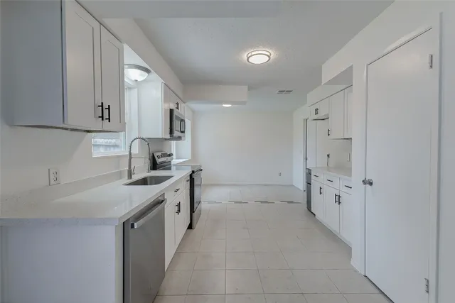 a kitchen with cabinets appliances a sink and a window