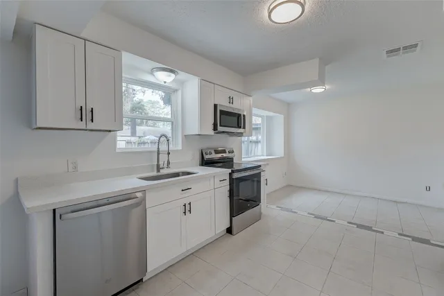 a kitchen with cabinets stainless steel appliances a sink and a window
