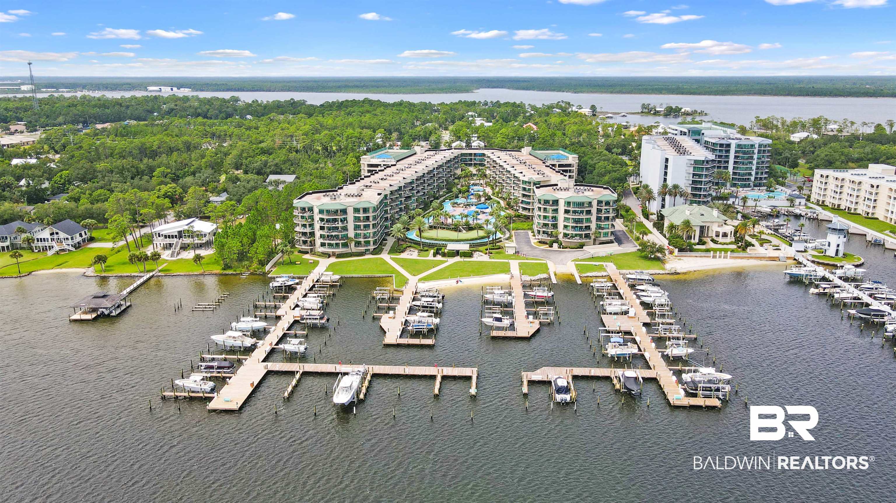 27580 Canal Road, Unit 1421 Orange Beach, AL 36561 - Photo 4 of 40 Expansive waterfront property featuring multiple residential buildings, private docks with numerous boat slips, a sandy shoreline, and a substantial green space