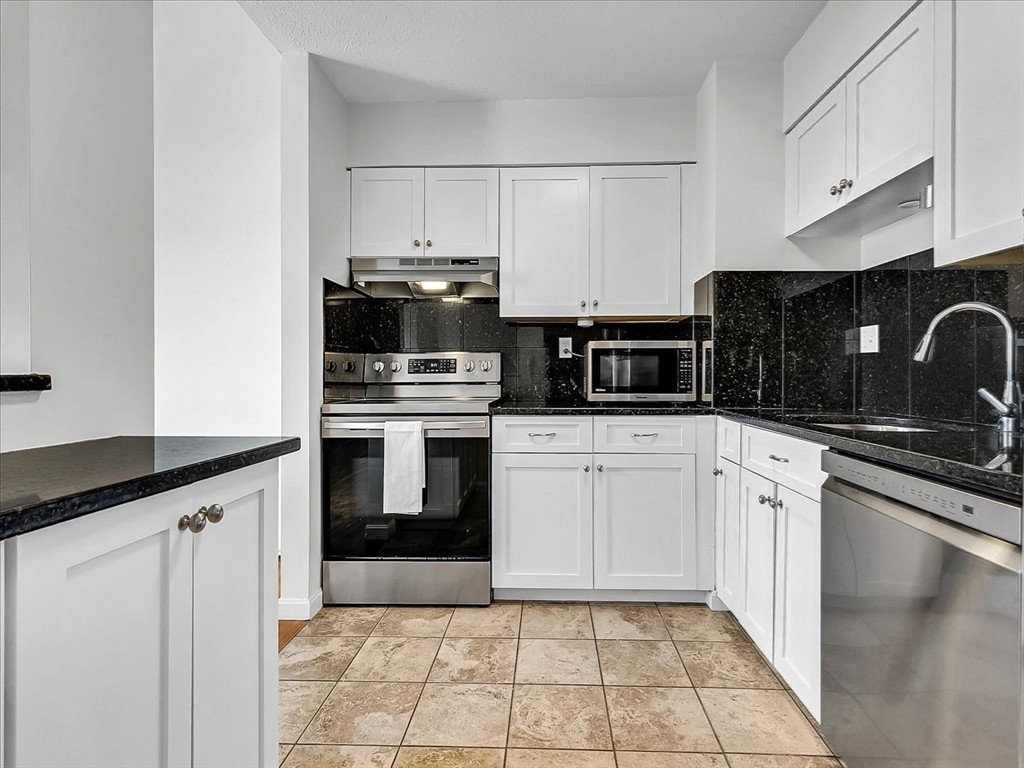 115 Water Street, Unit 14 Beverly, MA 01915 - Photo 16 of 38 a kitchen with granite countertop a sink a stove top oven and stainless steel appliances