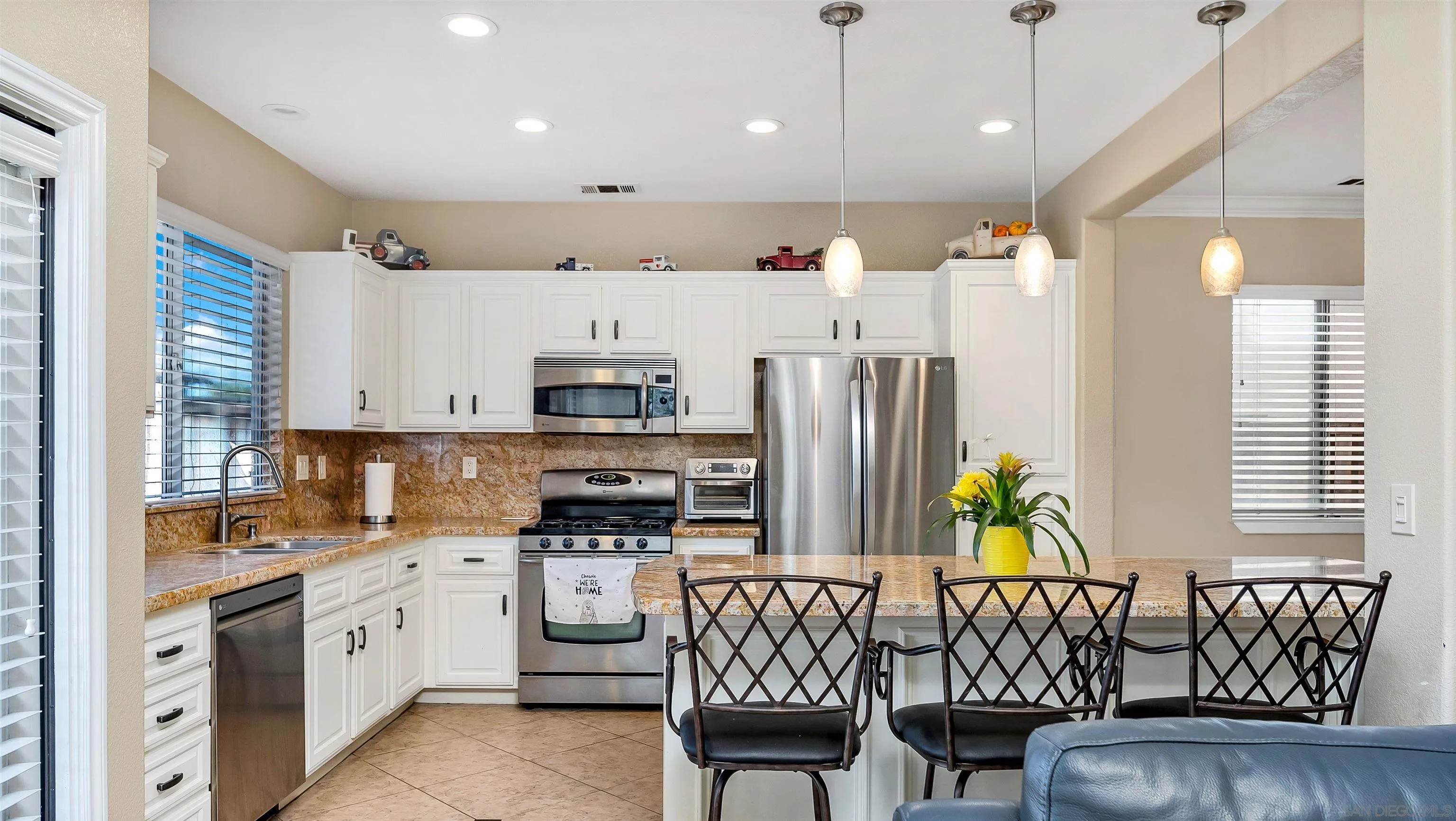 16163 Setting Sun Circle Riverside, CA 92503 - Photo 11 of 45 a kitchen with stainless steel appliances kitchen island granite countertop a table chairs and a refrigerator