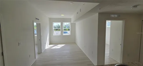 a view of an empty room with wooden floor and window