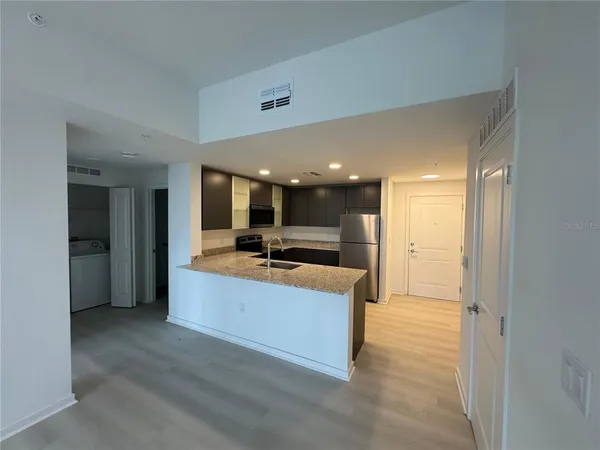 a kitchen with stainless steel appliances granite countertop a refrigerator a sink a stove and microwave