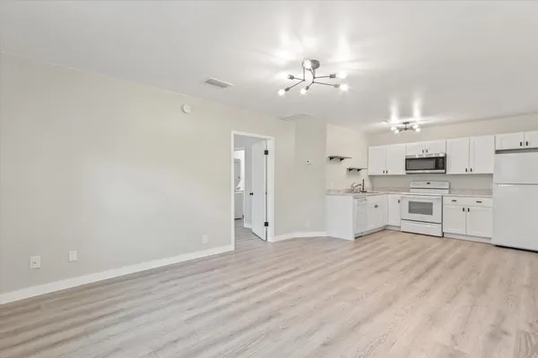 a large white kitchen with kitchen island a sink dishwasher a stove with cabinets and wooden floor