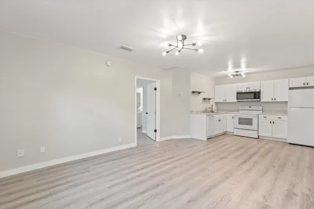 a large white kitchen with kitchen island a sink dishwasher a stove with cabinets and wooden floor