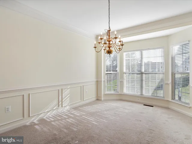 a view of an empty room with wooden floor and a kitchen