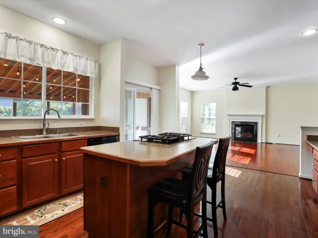 a kitchen with stainless steel appliances granite countertop a stove a refrigerator a sink dishwasher and wooden cabinets with wooden floor