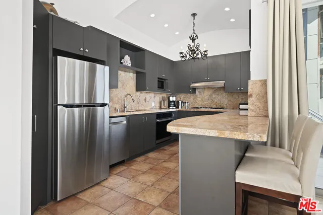 a kitchen with stainless steel appliances granite countertop a sink a refrigerator and a stove