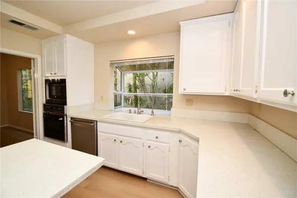 a kitchen with granite countertop white cabinets and refrigerator