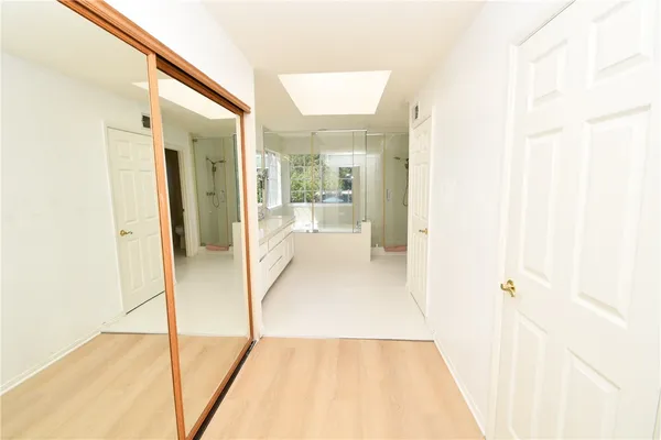 a view of a hallway with wooden floor and a bathroom