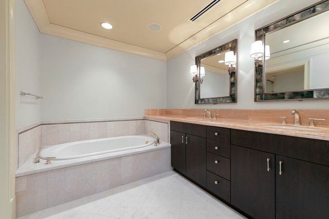 a bathroom with a tub a double vanity sink and mirror
