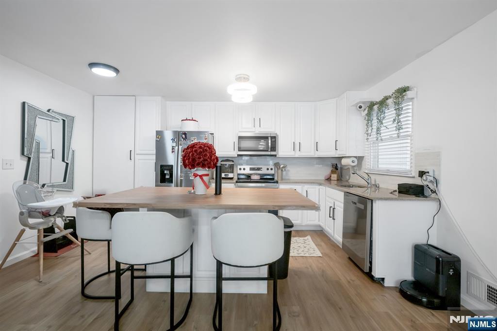 123 Chestnut Street Garfield, NJ 07026 - Photo 19 of 27 a kitchen with kitchen island a dining table chairs cabinets a sink and a window