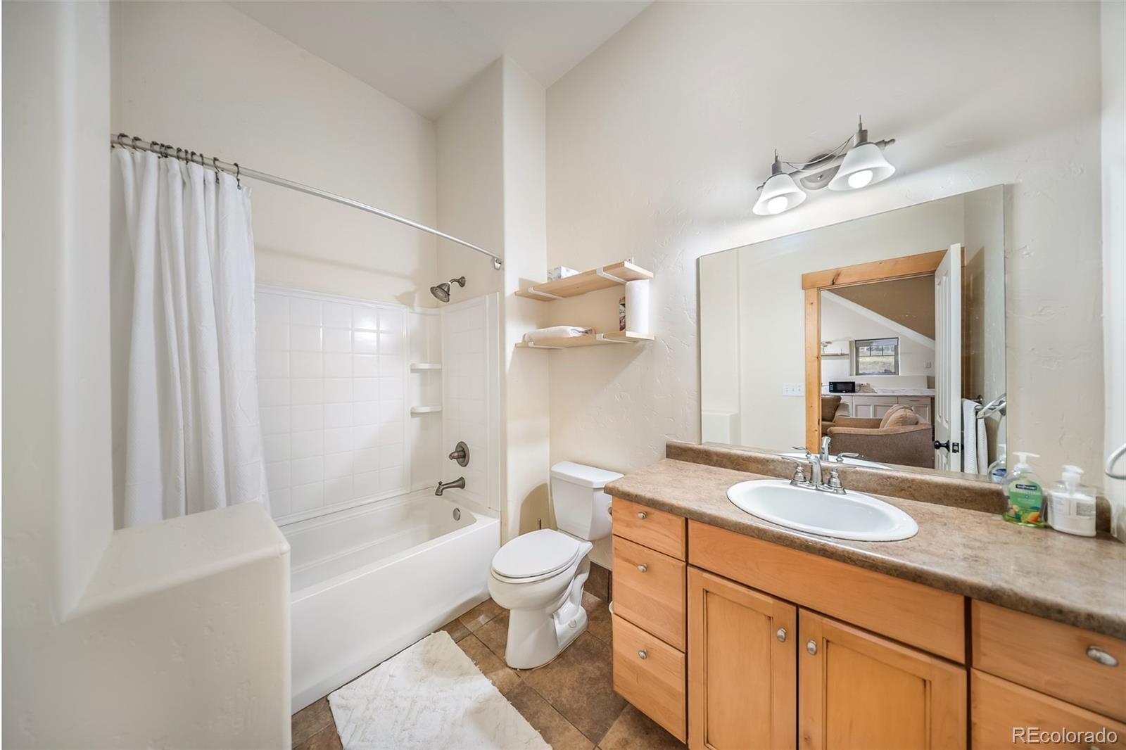 143 East Grand Avenue Hot Sulphur Springs, CO 80451 - Photo 24 of 37 a bathroom with a granite countertop sink a toilet a mirror a bathtub and shower