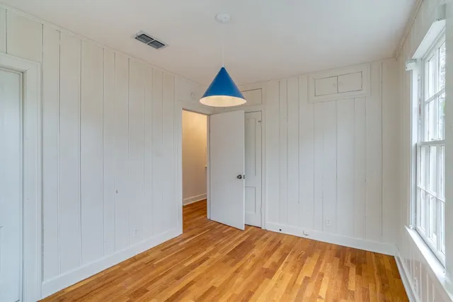 a view of empty room with wooden floor and fan
