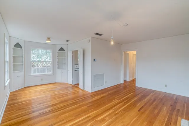 a view of empty room with wooden floor and fan