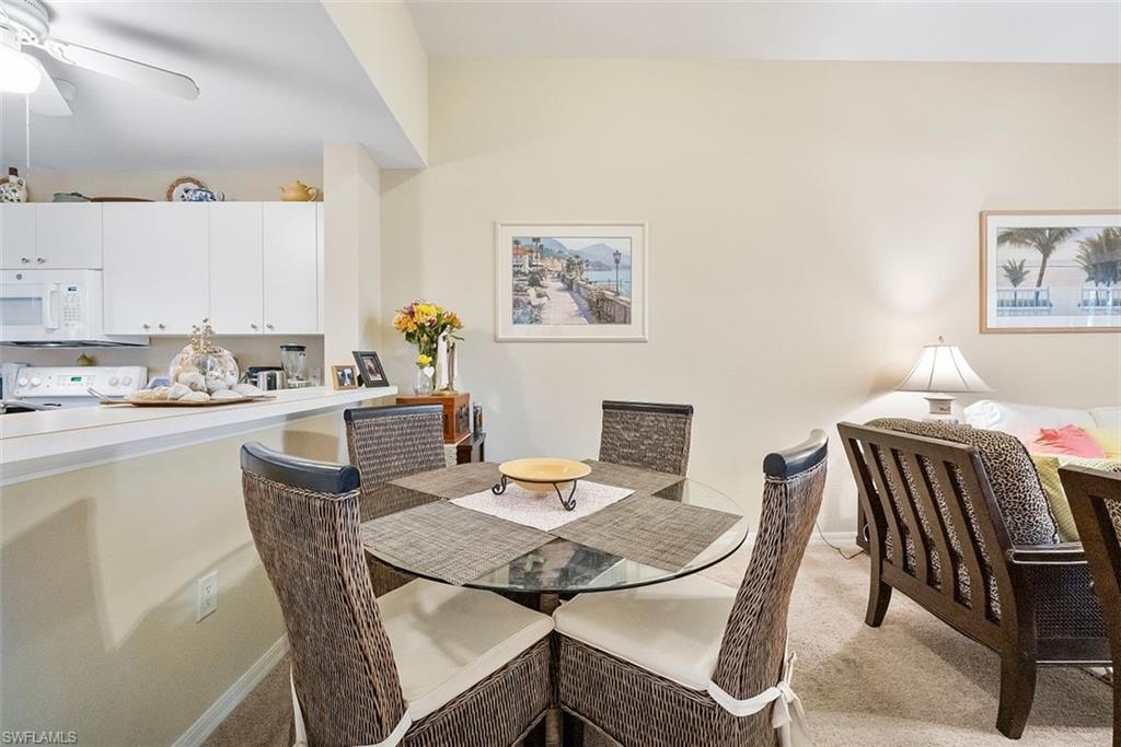 4500 Botanical Pl Circle, Unit 404 Naples, FL 34112 - Photo 12 of 31 Dining space with light carpet and ceiling fan