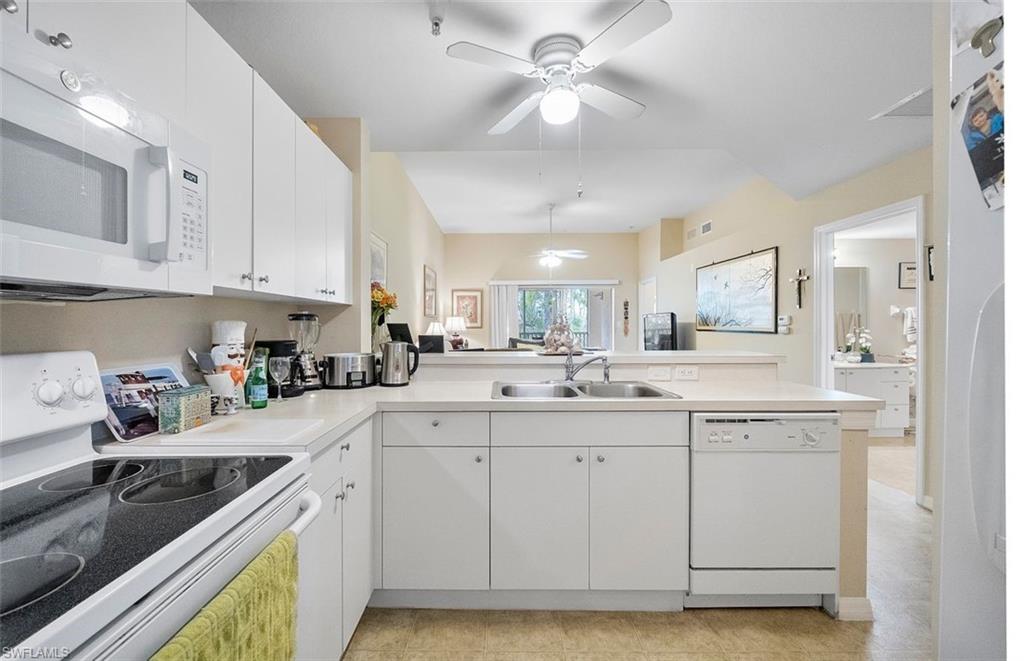 4500 Botanical Pl Circle, Unit 404 Naples, FL 34112 - Photo 6 of 31 Kitchen featuring white appliances, white cabinets, sink, and kitchen peninsula