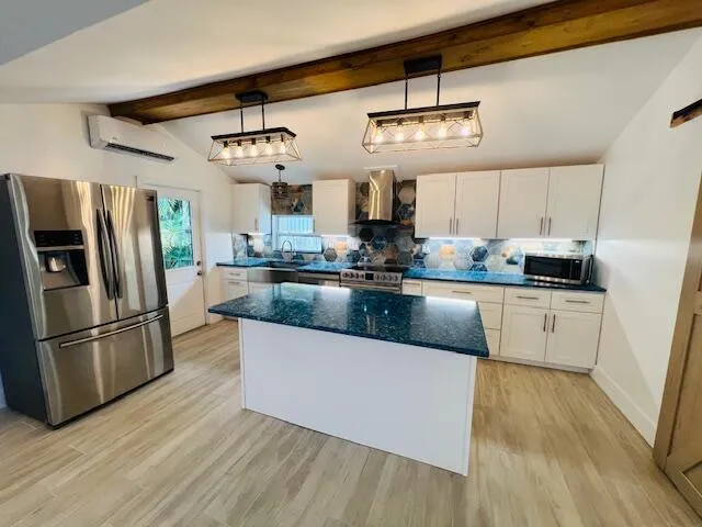 a kitchen with stainless steel appliances granite countertop a refrigerator a sink dishwasher a stove and a dining table with wooden floor