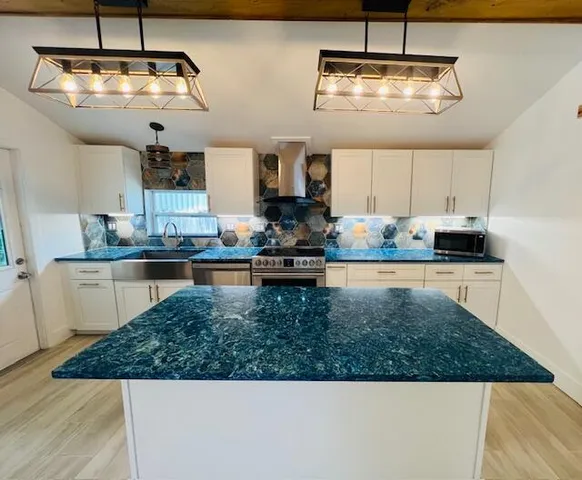 a kitchen with kitchen island granite countertop stainless steel appliances a stove a sink and a refrigerator